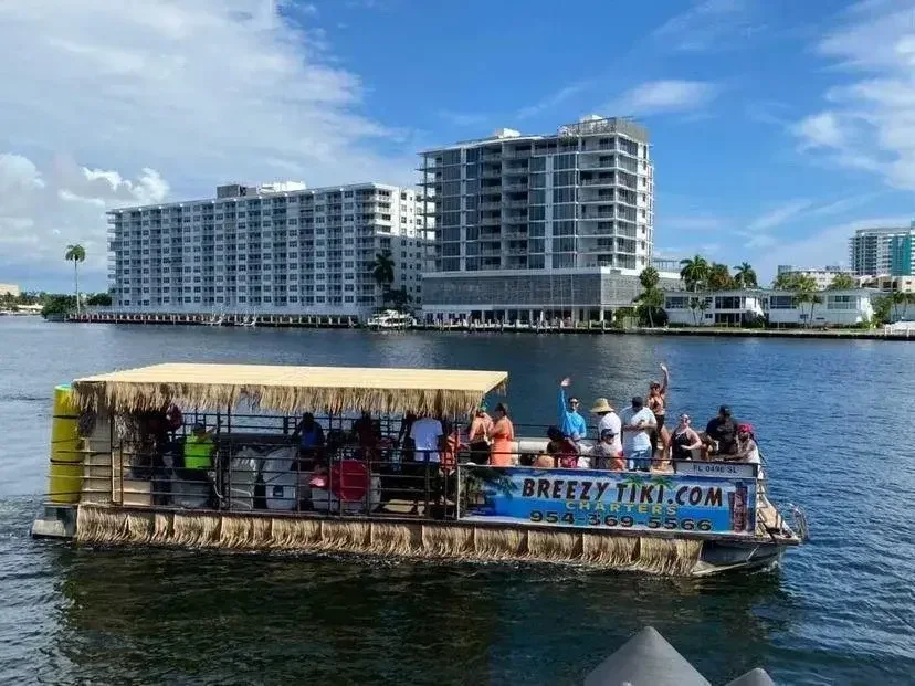 The 40-foot Breezy Tiki pontoon full of guests cruising the Fort Lauderdale intracoastal with the skyline behind